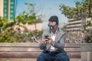 Happy businessman reading message on smartphone on street photo