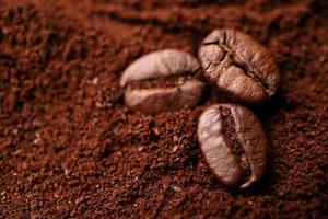 Closeup of three coffee beans at the mixed heap of roasted coffee with copy space for text. Concept of Coffee freshness photo