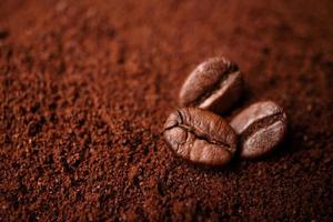 Closeup of three coffee beans at the mixed heap of roasted coffee with copy space for text. Concept of Coffee freshness photo