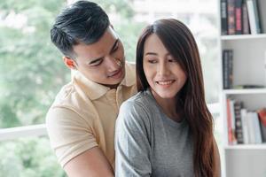 Happy couple sitting on the sofa and being a man teases his girlfriend with love in the living room and relax. Concept of romantic on valentine day. Proposal and marriage photo