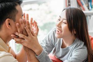 Happy couple sitting on the sofa and being a man teases his girlfriend with love in the living room and smile. Concept of romantic on valentine day. Proposal and marriage photo