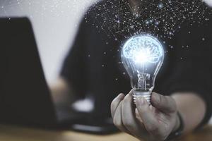 Businessman hand holding lightbulb with glowing virtual brain and  connection line to creative smart thinking for inspiration and innovation with network concept. photo