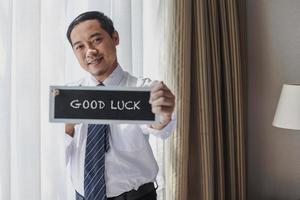 Asian Businessman in white shirt and tie with sign board saying Good Luck photo