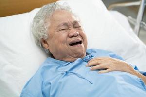 Paciente asiático mayor o anciana mujer siente dolor en el pecho y el corazón en la cama en la sala del hospital de enfermería foto