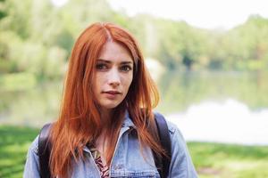 authentic young woman wearing denim jacket and backpack outdoors on a hike photo