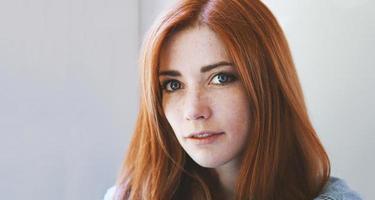 indoor portrait of young woman with red hair and freckles photo