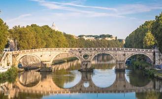 Bridge on Tiber river in Rome, Italy. Vatican Basilica cupola in background with sunrise light. photo