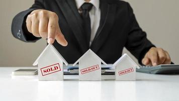 un hombre de negocios elige un modelo de casa con un mensaje a la venta sobre ideas comerciales de bienes raíces y préstamos hipotecarios. foto