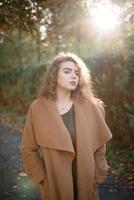 Beautiful elegant woman standing in a park in autumn photo