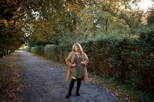 hermosa mujer elegante de pie en un parque en otoño foto