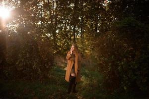 hermosa mujer elegante de pie en un parque en otoño foto