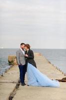 Wedding photo session of a couple on the seashore. Blue wedding dress on the bride.