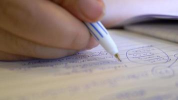 Close up hand of woman sitting at desk holding pen making notes in notebook, writing start up business ideas and plans at home, creative thoughts. Creating list and making key highlight concept video