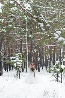 Beautiful bride posing with bouquet in snowy forest. Winter wedding. Artwork. Full length portrait photo