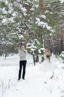 Handsome groom in beige pullover on background of blurred bride in snowy forest. Winter wedding. Copy space photo