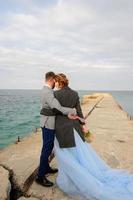 Wedding photo session of a couple on the seashore. Blue wedding dress on the bride.