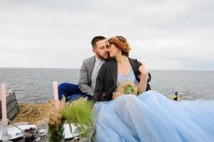 sesión de fotos de boda de una pareja a la orilla del mar. vestido de novia azul en la novia.