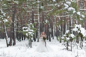 novia y novio en jerseys de punto beige en bosque nevado. los recién casados están tocando frentes. boda de invierno. copie el espacio