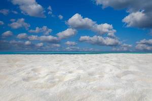 Closeup of sand on beach and blue summer sky. Panoramic beach landscape. Empty tropical beach and seascape. Blue sky, soft sand, calmness, tranquil relaxing sunlight, summer mood. Travel vacation photo