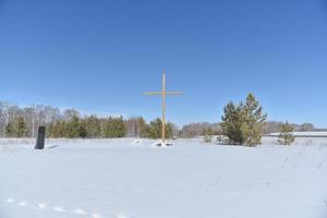 Christian cross in the field in winter in the forest photo