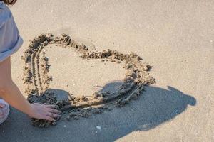 blurred of drawing heart on a yellow sand at a beautiful seascape background. Horizontal composition. photo