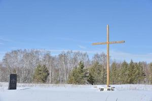 Christian cross in the field in winter in the forest photo