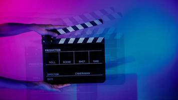 Hand holds empty film making clapperboard on color background in studio photo