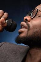 A black African American is emotionally singing into a microphone. Close-up studio portrait.