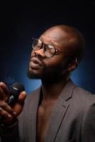 A black African American is emotionally singing into a microphone. Close-up studio portrait. photo