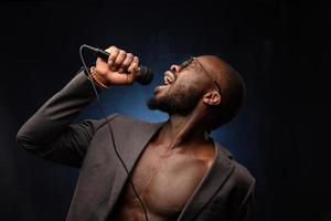 A black African American is emotionally singing into a microphone. Close-up studio portrait. photo