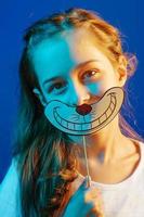 chica de fondo azul con una sonrisa en un trozo de papel. retrato con luz de color. foto
