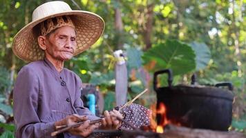 una anciana encendiendo un fuego para cocinar video