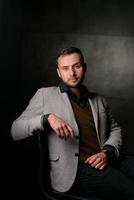 Studio portrait of a young caucasian man in a black blazer, looking at the camera, standing against plain studio background photo