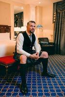 handsome mature courageous stylish man scotsman in kilt in fancy hotel room. Style, fashion, lifestyle, culture, travel, ethnic concept.