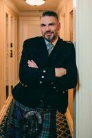 handsome mature courageous stylish man scotsman in kilt in fancy hotel room. Style, fashion, lifestyle, culture, travel, ethnic concept. photo