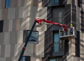 Milan italy 8 September 2020 Construction worker on a boom lift on the side of a building photo