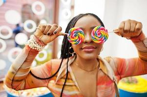 African american millennial lady at candy shop with lolipops cover her eyes. photo