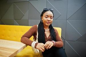 African american woman in brown shirt and black pants sit in cafe. photo