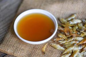 fish sauce on white bowl and small dried fish on sack, fish sauce obtained from fermentation fish or small aquatic animal, fermented foods photo