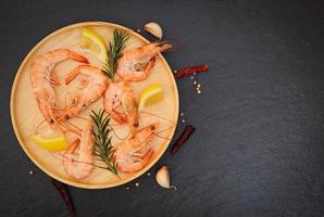 Fresh shrimps served on wooden plate with rosemary lemon , boiled peeled shrimp prawns cooked in the seafood restaurant - top view photo