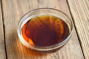 fish sauce on glass bowl and wooden background, fish sauce obtained from fermentation fish or small aquatic animal, fermented foods photo