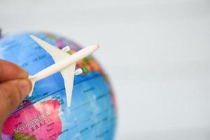 Business man holding airliner aircraft plane on world globe background - worldwide travel concept photo