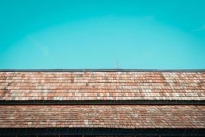 Old wooden roof texture with blue sky background. photo