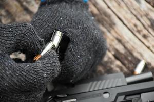 Two hands reloading 9mm bullets full metal jacket rounds into a black magazine. Soft and selective focus on bullets. photo