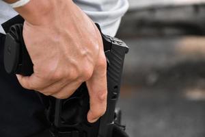 Pistola automática de 9 mm sujeta en la mano en la funda, lista para sacar y lista para disparar al objetivo por delante, concepto para la profesión de seguridad y deporte de tiro en todo el mundo. foto