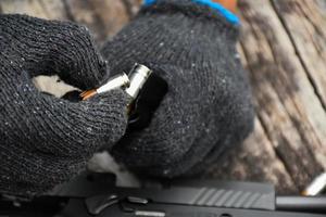 Two hands reloading 9mm bullets full metal jacket rounds into a black magazine. Soft and selective focus on bullets. photo