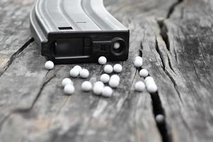 Closeup of white plastic bullets of airsoft gun or bb gun on wooden floor, soft and selective focus on white bullets. photo