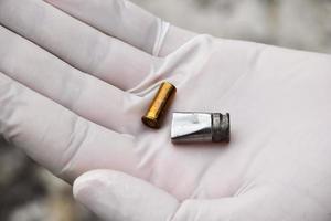 Forensic officers holds physical evidence which is the bullet shell up to eye level to determine the size and type of ammunition at the murder. photo