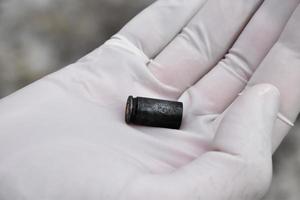 Forensic officers holds physical evidence which is the bullet shell up to eye level to determine the size and type of ammunition at the murder. photo