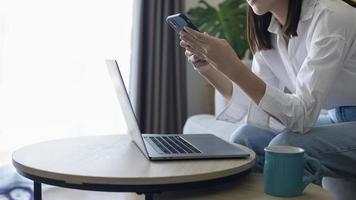 Young happy woman relaxing and using smart phone at home, social media and technology concept. photo